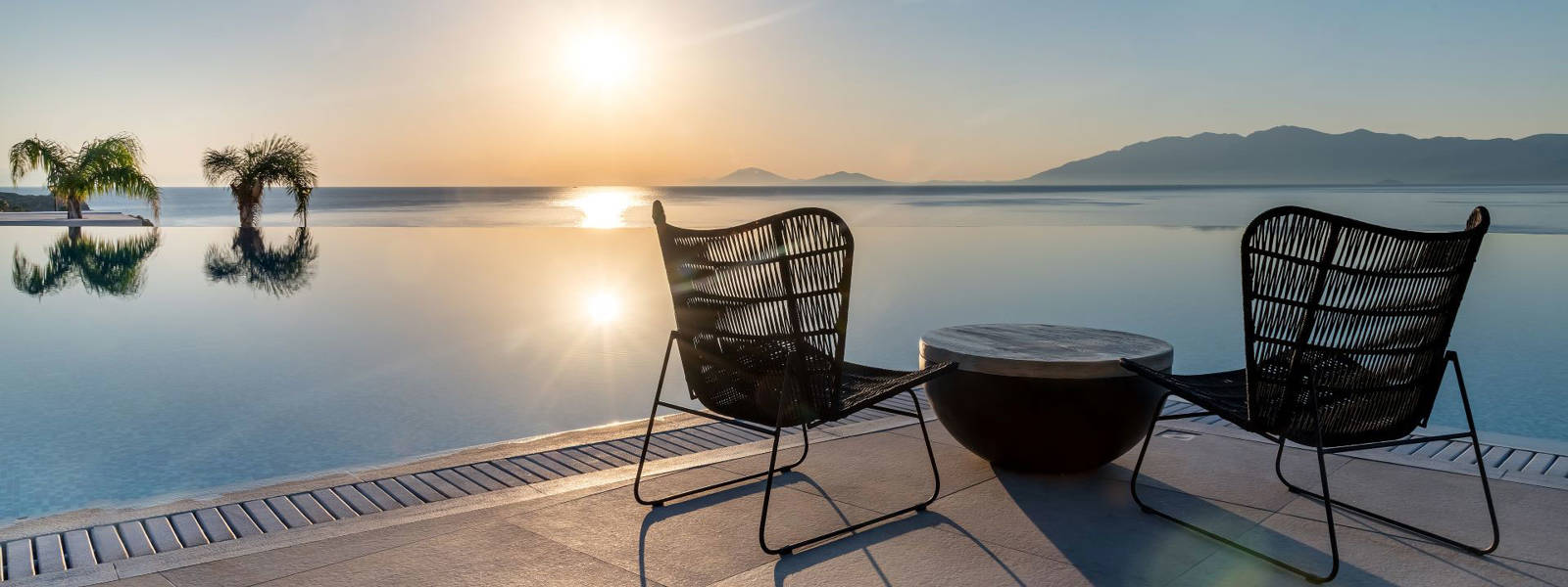 Table with chairs in front of the pool at sunrise