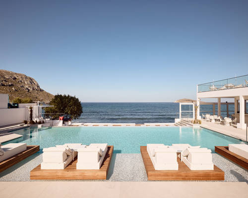 Poolside and sunbeds with the sea as background