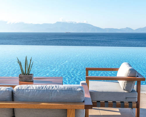 Two chairs, a table and the view of the pool and the beach